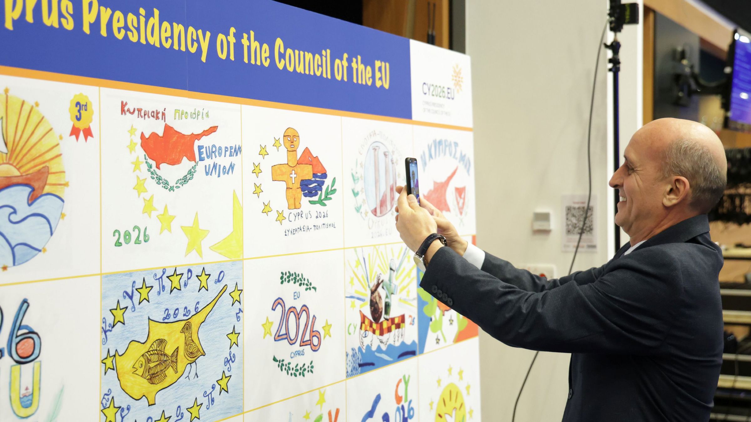 a person taking photographs of a panel with school chidren artwork