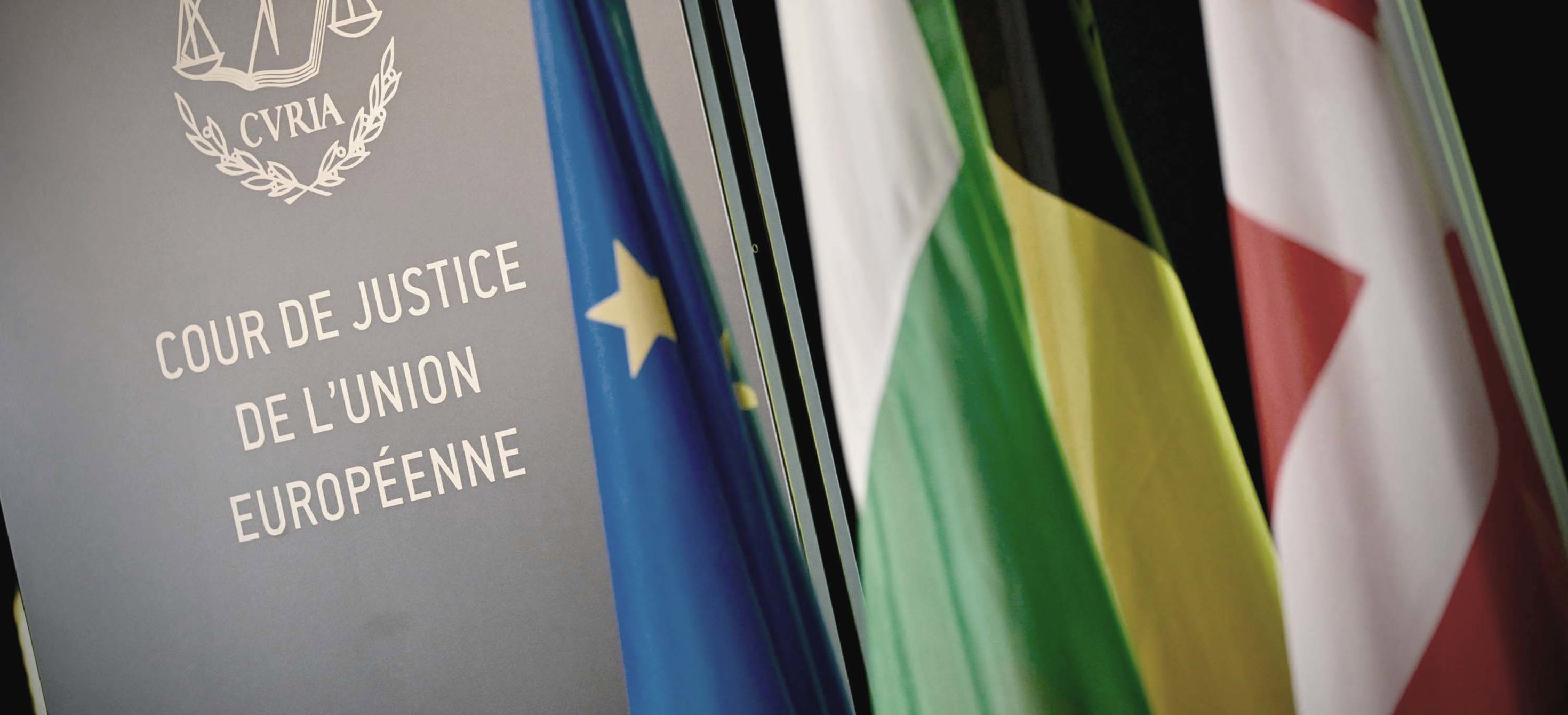 Sign of the Court of Justice of the EU next to European and National flags