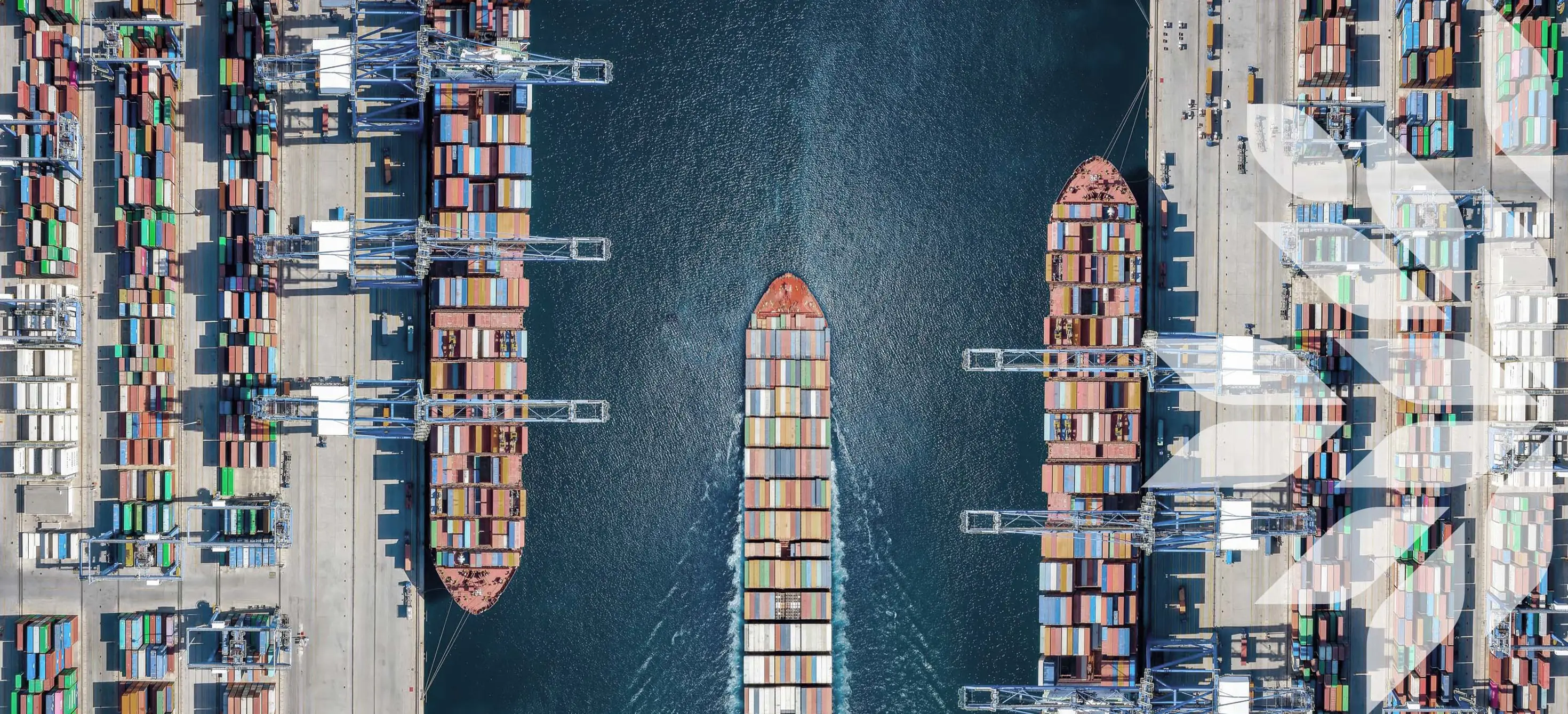Aerial view looking down on a large container ship terminal with loading activity and vessel traffic 
